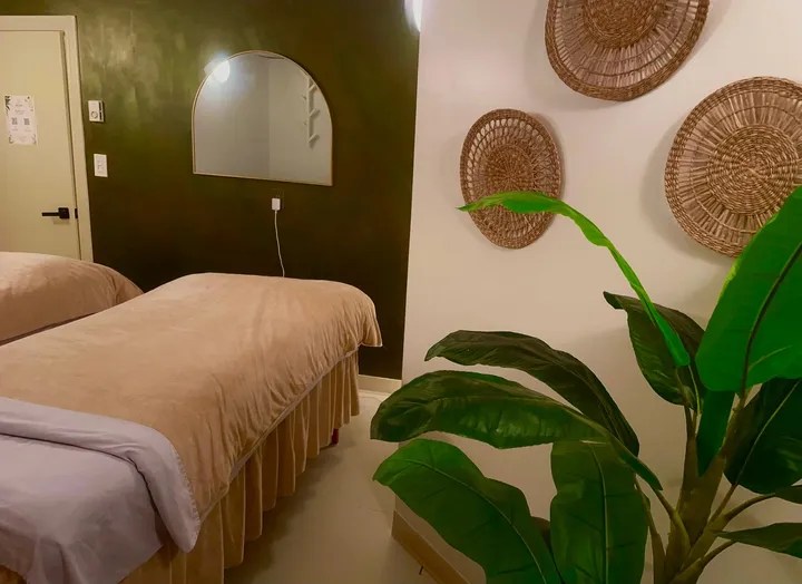 The couples room with two massage tables, woven wall baskets and a large plant