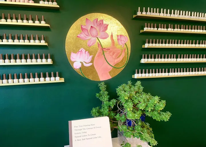 The gold lotus painting on the green wall, between shelves of nail polish