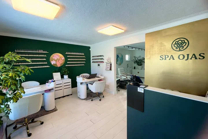 The reception area with the gold SPA OJAS sign, the nail stations and the lotus painting on the green wall